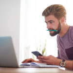 a guy with a pencil in his teeth and a phone in his hand